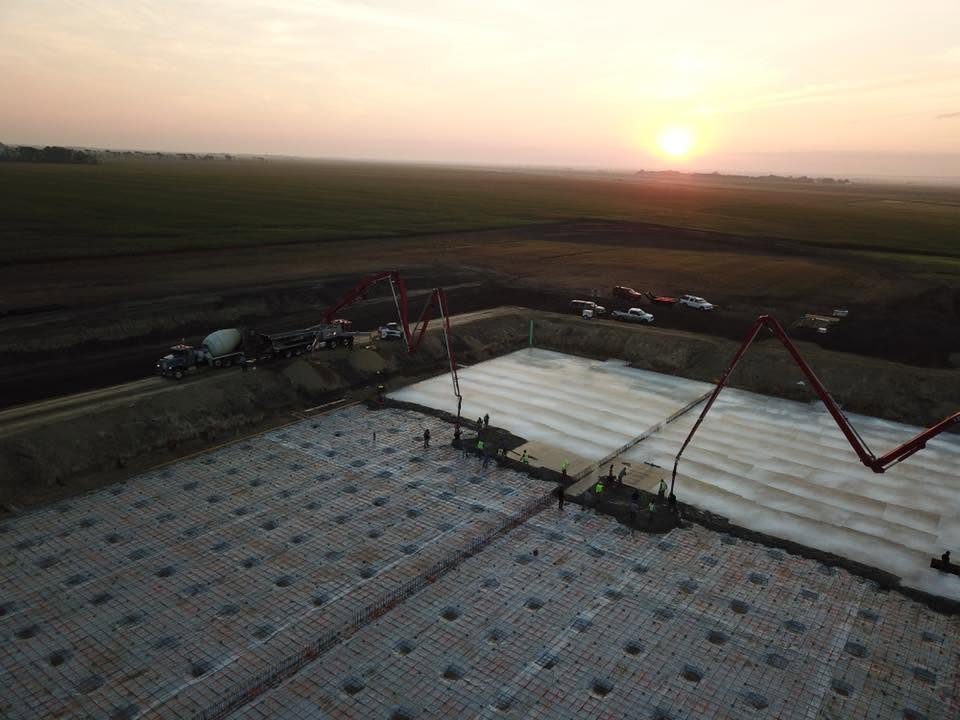 Aerial sunrise view of a commercial slab pour with two pump trucks