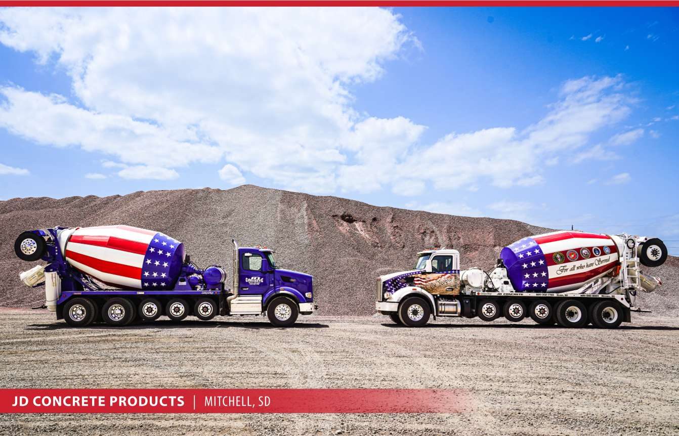 Two JD Concrete flag-wrapped mixer trucks
