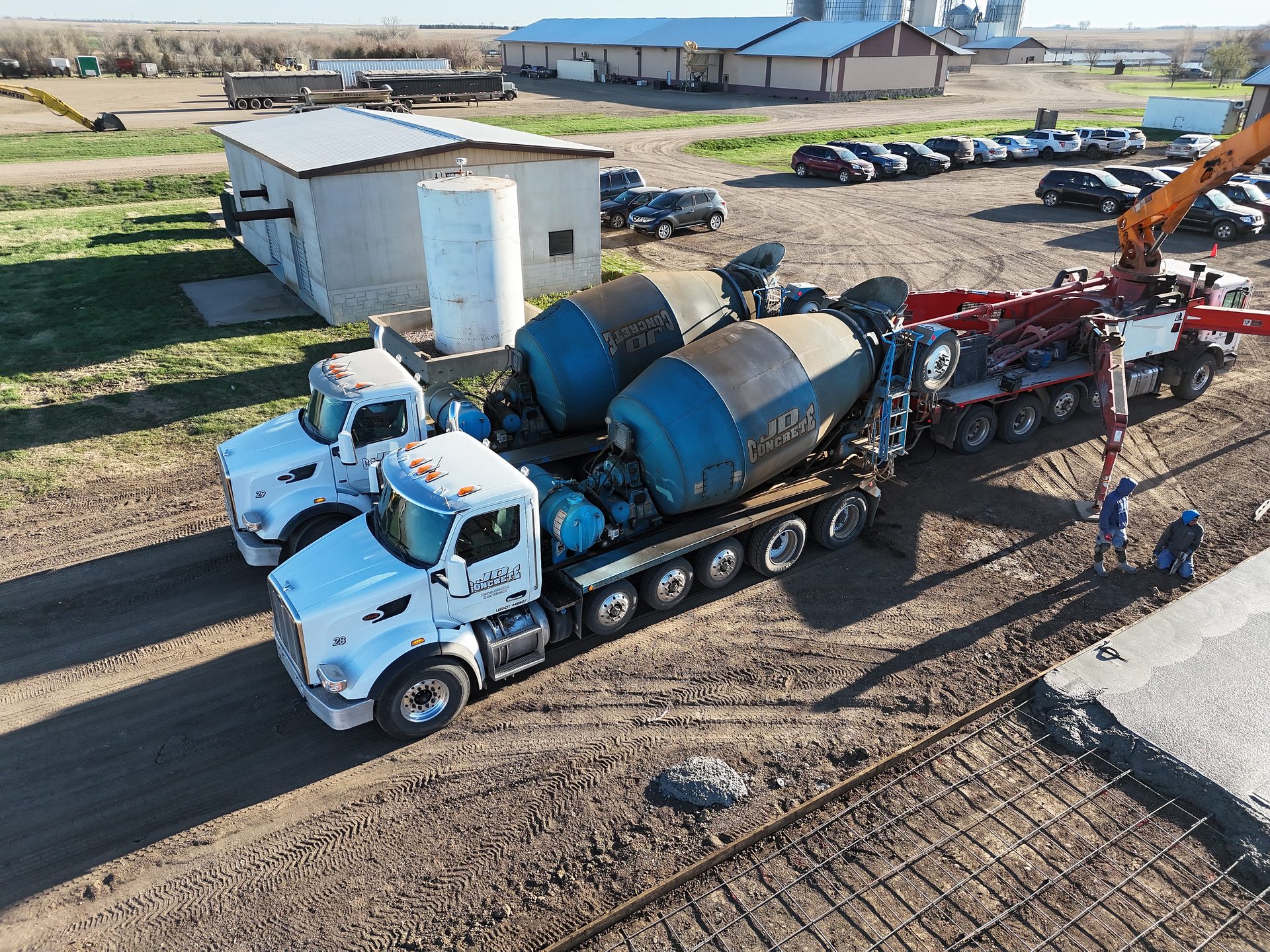 Aerial view of JD Concrete mixer trucks and a pump truck on a job site